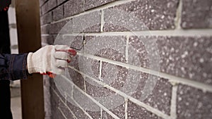 The builder carefully makes a brick wall, a close-up of a skilled craftsman laying a large masonry of bricks, the