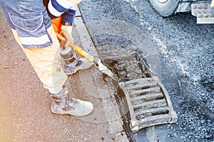 Builder cleaning blocked road gully with shovel and vacuum excavator