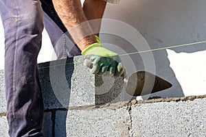 A builder constructs a wall of aerated concrete blocks