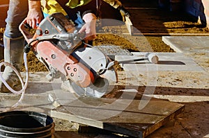 Builder cutting concrete slabs with petrol concrete saw and a diamond blade during external footpath paving works close up