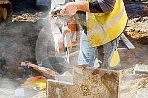 Builder cutting concrete slabs with petrol concrete saw and a diamond blade during external footpath paving works close up