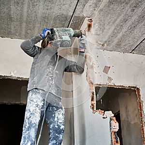 Builder deconstructing interior septum using jackhammer in flat.
