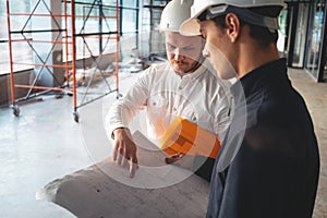 Builder discussing blueprint with architect building under construction