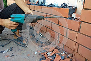The builder dismantles the brick in the wall with a punch