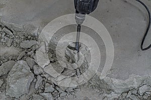 A builder dismantles a perforator drill breaks the concrete floor at a construction site