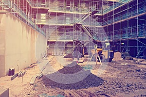 Builder driving dumper truck and excavator on new building construction site. Surveying equipment on construction site