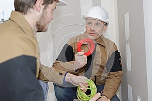 Builder engineer and co-worker screwing equipment in fuseboard