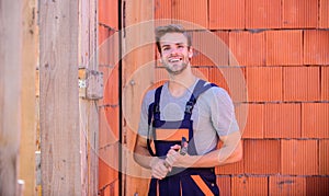 Builder enjoy success. worker brick wall background. building and construction. man builder in work clothes