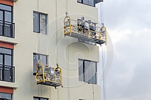 Builder at facade construction work hanging cradles.
