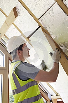 Builder Fitting Insulation Boards Into Roof Of New Home