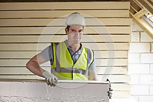 Builder Fitting Insulation Boards To Roof Of New House