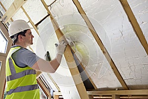 Builder Fitting Insulation Into Roof Of New Home