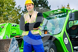 Builder in front of construction machinery