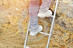 Builder going up the ladder to get out of trench