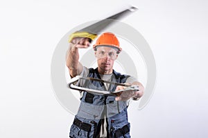 A builder with hacksaws in a helmet mocks. On a light background photo