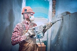 Builder with hammer breaking wall indoors