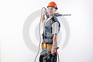 A builder with a hammer drill on his shoulder, in a helmet, smiles