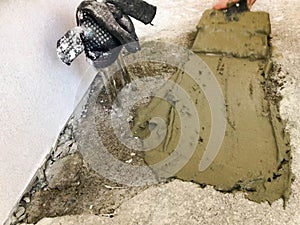 Builder hands with a metal spatula plaster the wall, pours the screed with plaster, tile glue, cement for the repair