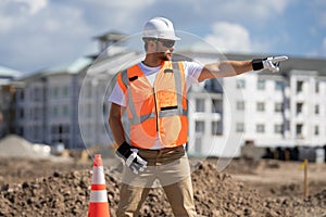 Builder in a hard hat working on a construction project at a site. A builder worker in a helmet near building