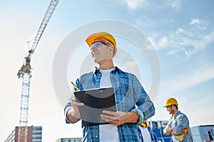 Builder in hardhat with clipboard at construction