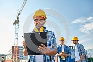 Builder in hardhat with clipboard at construction photo