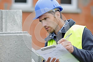 builder in hardhat with clipboard outdoors