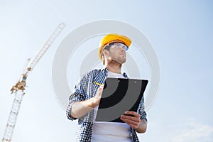 Builder in hardhat with clipboard outdoors