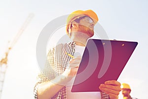 Builder in hardhat with clipboard outdoors