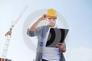 Builder in hardhat with clipboard outdoors