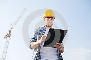 Builder in hardhat with clipboard outdoors