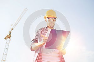 Builder in hardhat with clipboard outdoors