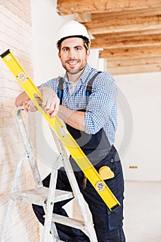 Builder in hardhat with clipboard and pencil indoors