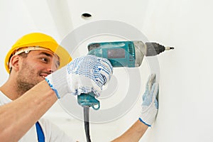 Builder in hardhat with drill perforating wall