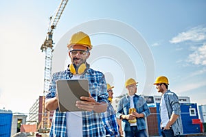 Builder in hardhat with tablet pc at construction