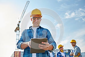 Builder in hardhat with tablet pc at construction