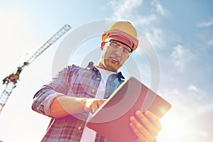 Builder in hardhat with tablet pc at construction