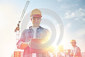 Builder in hardhat with tablet pc at construction