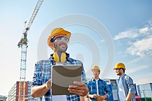 Builder in hardhat with tablet pc at construction