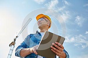 Builder in hardhat with tablet pc at construction