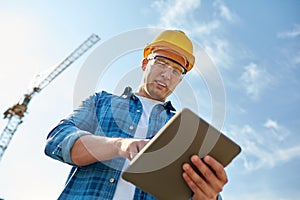 Builder in hardhat with tablet pc at construction