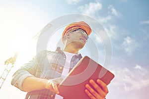 Builder in hardhat with tablet pc at construction photo