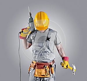 Builder in a helmet with a hammer and a drill