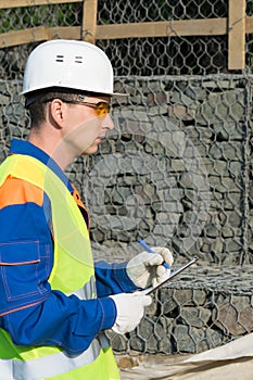 A builder in a helmet records violations in the protocol during the commissioning of the object photo