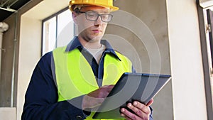 builder in helmet and safety west with tablet pc