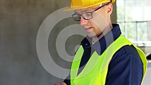 builder in helmet and safety west with tablet pc