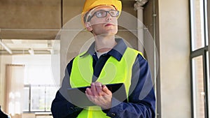 builder in helmet and safety west with tablet pc