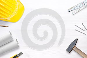 Builder helmet, tools and plans on white desk with free space fot text photo