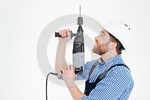 Builder in helmet using drill and looking up