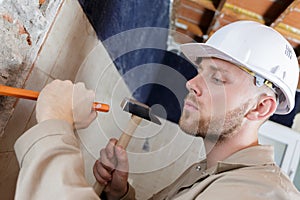 builder hitting wall with hammer