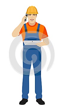 Builder holding digital tablet and talking on the mobile phone